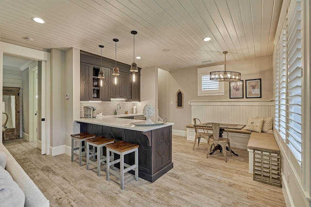 kitchen featuring kitchen peninsula, wooden ceiling, hanging light fixtures, and a breakfast bar area