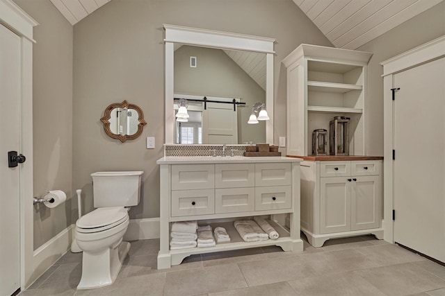 bathroom with tile patterned flooring, vanity, vaulted ceiling, and toilet