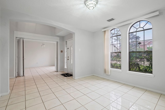 unfurnished room with a textured ceiling and light tile patterned flooring