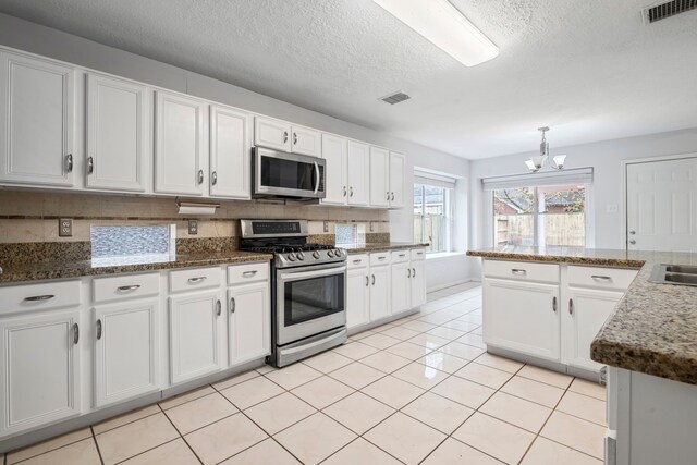 kitchen featuring white cabinets, appliances with stainless steel finishes, a textured ceiling, and a chandelier