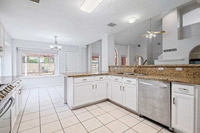 kitchen with appliances with stainless steel finishes, a textured ceiling, sink, stone countertops, and white cabinets