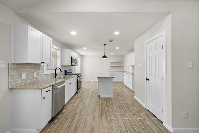 kitchen featuring white cabinets, stainless steel appliances, and decorative light fixtures