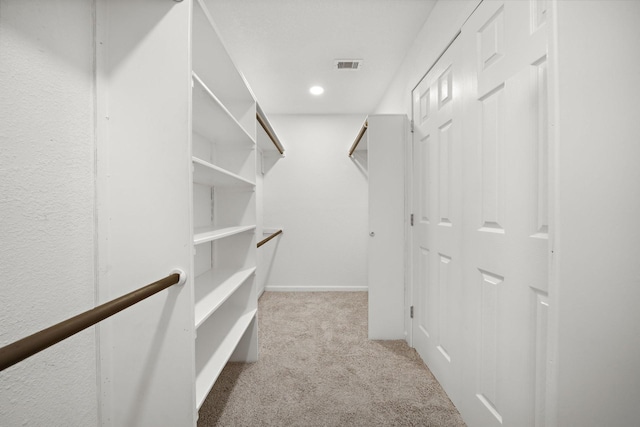 walk in closet featuring light carpet