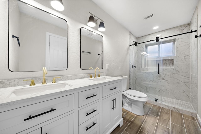 bathroom with vanity, toilet, and a shower with door