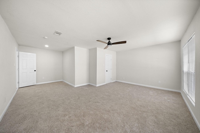 spare room with light colored carpet, ceiling fan, and a healthy amount of sunlight