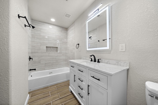 full bathroom with toilet, vanity, and tiled shower / bath