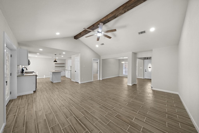 unfurnished living room with lofted ceiling with beams, ceiling fan, and sink