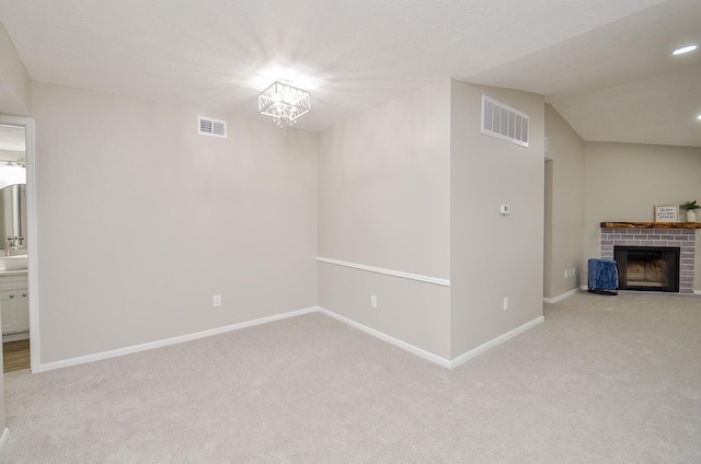 interior space featuring a notable chandelier, a fireplace, light colored carpet, and vaulted ceiling