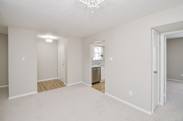 unfurnished room featuring sink, light colored carpet, and a textured ceiling