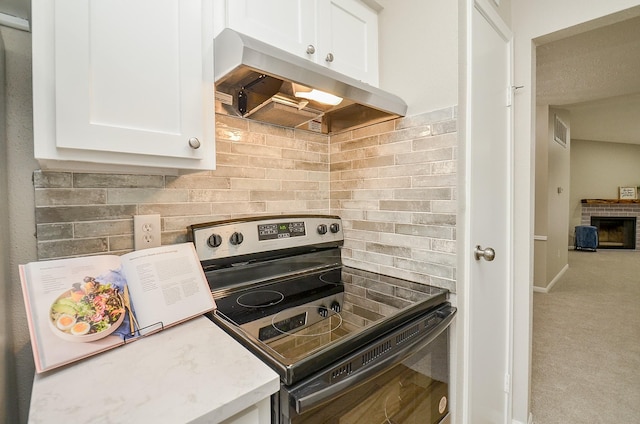 kitchen featuring extractor fan, tasteful backsplash, white cabinetry, carpet flooring, and stainless steel electric range