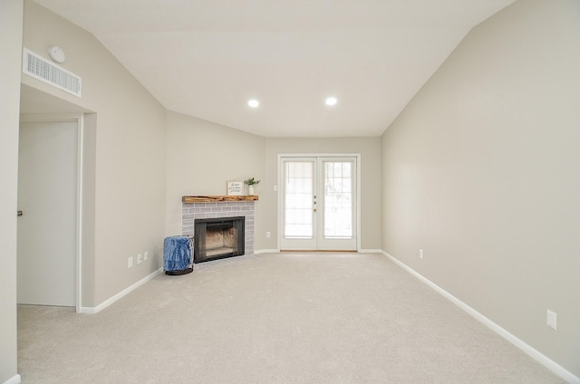 unfurnished living room featuring french doors, lofted ceiling, light carpet, and a brick fireplace