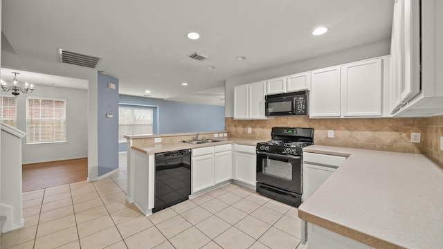 kitchen with kitchen peninsula, black appliances, light tile patterned floors, an inviting chandelier, and white cabinets