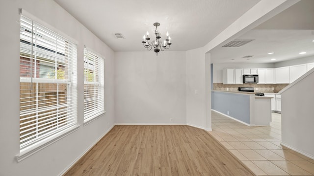 unfurnished dining area with a notable chandelier and light wood-type flooring