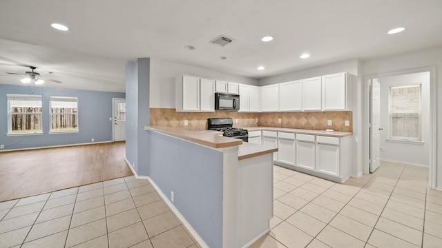 kitchen featuring black appliances, white cabinets, light tile patterned floors, and kitchen peninsula