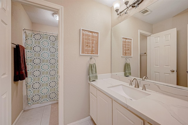 bathroom with a textured ceiling, an inviting chandelier, tile patterned floors, and vanity