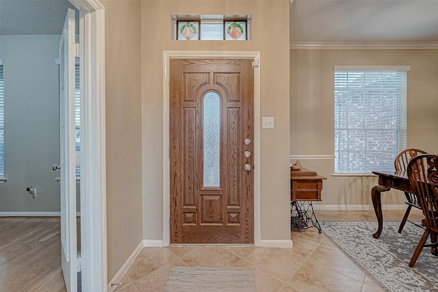 foyer entrance with light tile patterned floors and ornamental molding