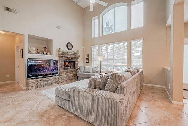 tiled living room with ceiling fan, a fireplace, and a high ceiling