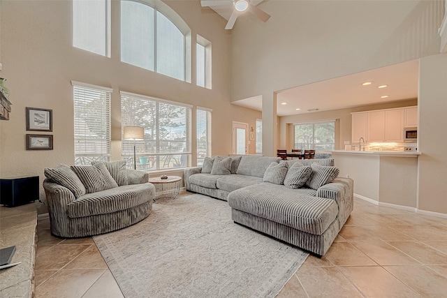 tiled living room with ceiling fan, a high ceiling, and sink