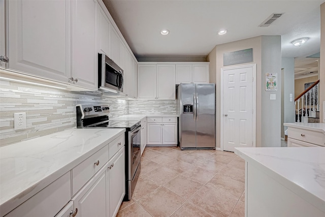 kitchen with light stone counters, white cabinetry, and appliances with stainless steel finishes