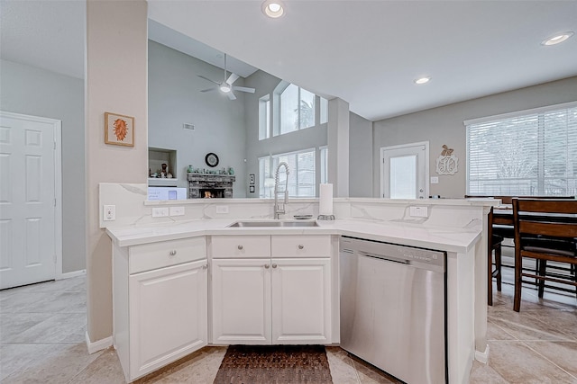 kitchen featuring ceiling fan, a fireplace, stainless steel dishwasher, sink, and white cabinetry