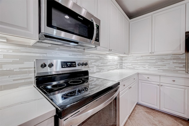 kitchen featuring light tile patterned floors, white cabinetry, stainless steel appliances, decorative backsplash, and light stone countertops