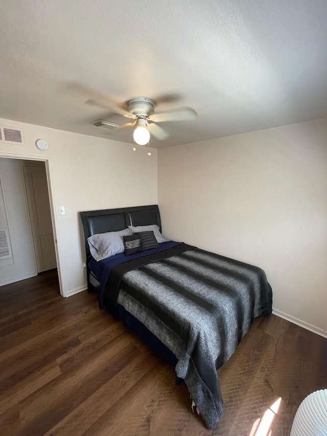 bedroom with dark hardwood / wood-style flooring, ceiling fan, and a textured ceiling