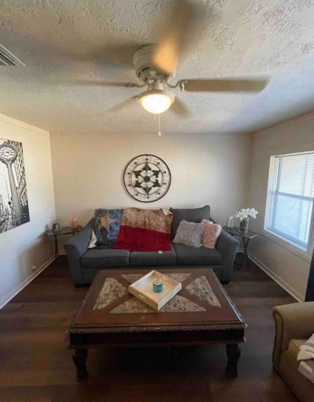 living room featuring ceiling fan, dark hardwood / wood-style flooring, and a textured ceiling