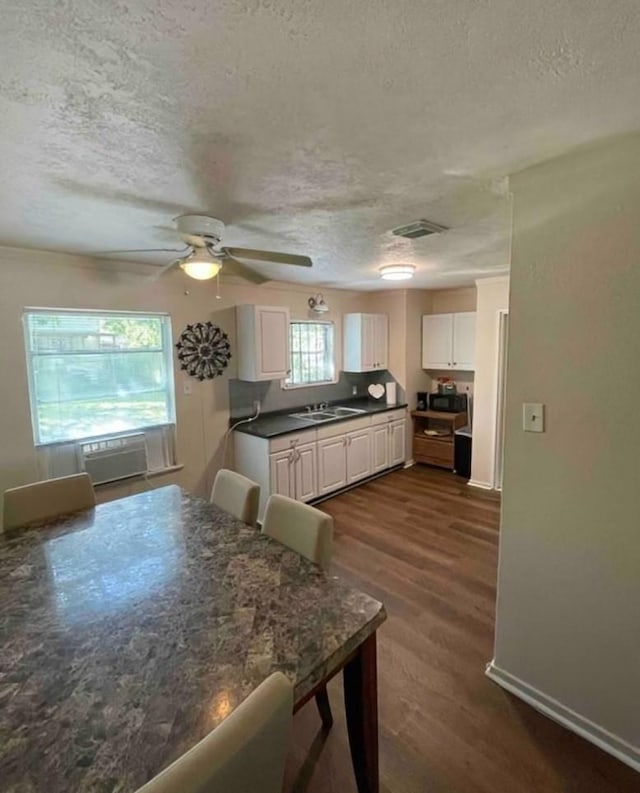 kitchen with sink, dark wood-type flooring, white cabinets, and a textured ceiling