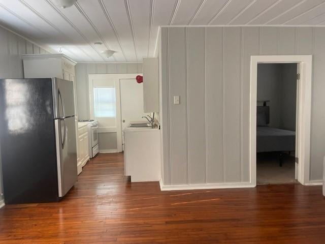 kitchen featuring stainless steel fridge, dark wood-type flooring, sink, white cabinets, and white stove