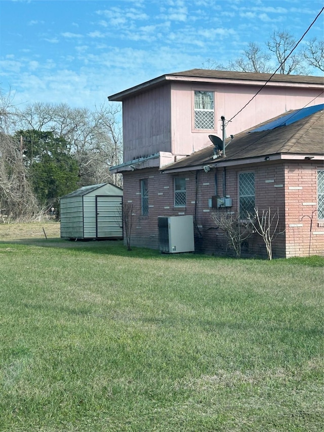 back of property featuring central AC, a yard, an outdoor structure, and a storage unit