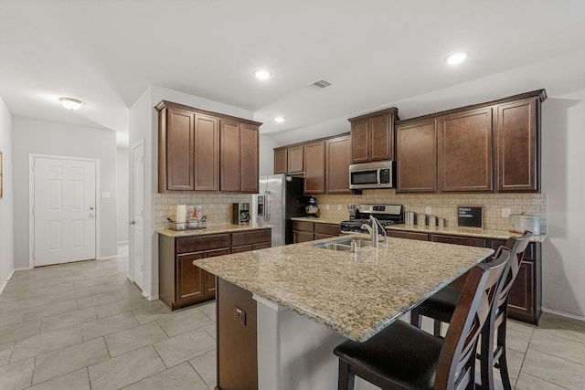 kitchen featuring light tile patterned flooring, sink, stainless steel appliances, and a kitchen island with sink