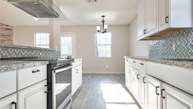 kitchen featuring white cabinetry, backsplash, electric range, and a chandelier