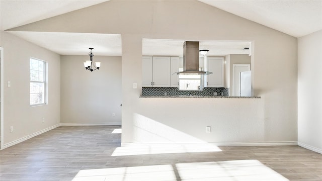 kitchen with island exhaust hood, backsplash, an inviting chandelier, and lofted ceiling