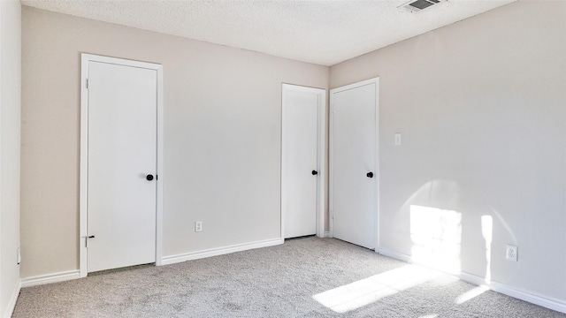 spare room with a textured ceiling and light colored carpet