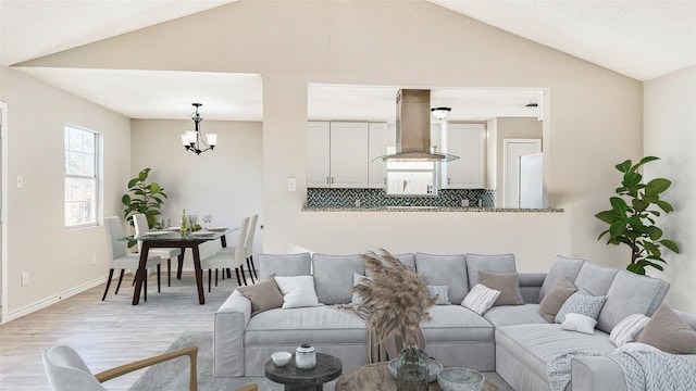 living room featuring an inviting chandelier, vaulted ceiling, and light wood-type flooring