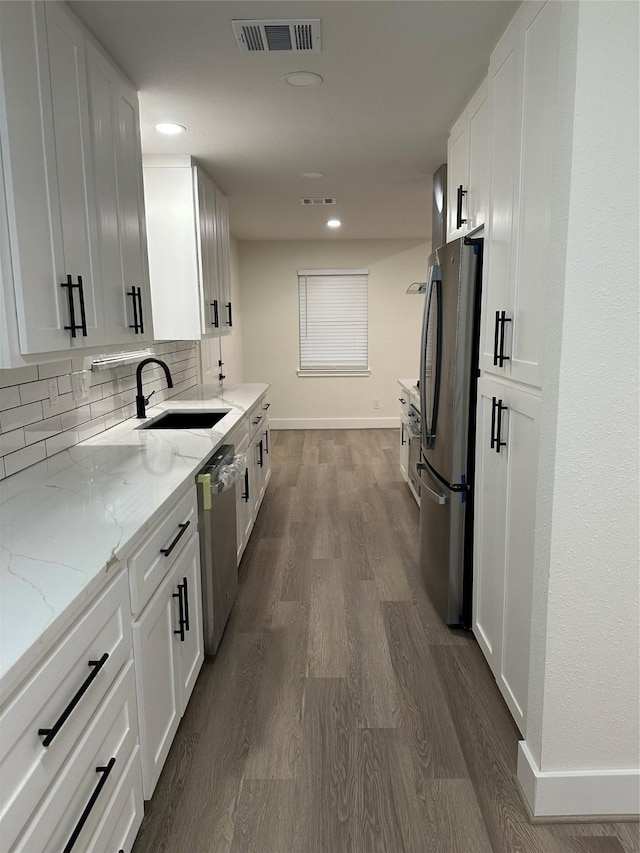 kitchen featuring white cabinets, sink, light stone countertops, and stainless steel appliances