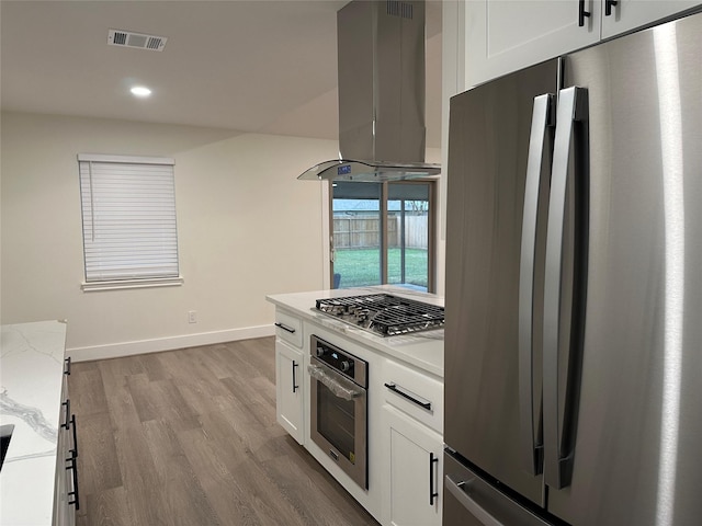 kitchen with light wood-type flooring, white cabinetry, island exhaust hood, and appliances with stainless steel finishes