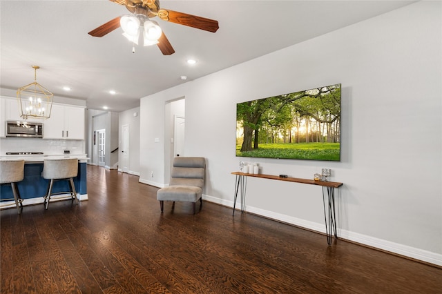 living area with dark hardwood / wood-style floors and ceiling fan with notable chandelier