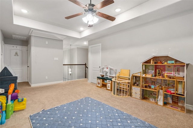 rec room featuring ceiling fan, a tray ceiling, and carpet floors