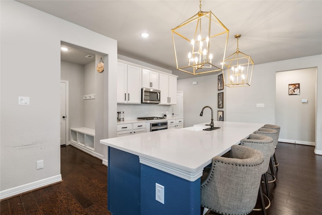 kitchen featuring hanging light fixtures, stainless steel appliances, sink, and a center island with sink