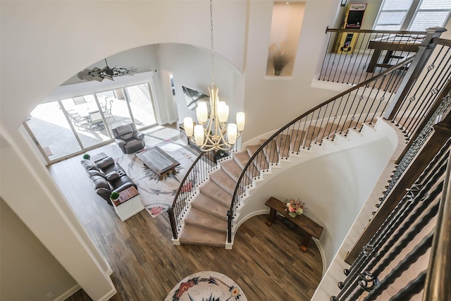 staircase featuring wood-type flooring and ceiling fan with notable chandelier