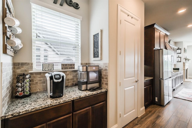 kitchen featuring stainless steel fridge, dark hardwood / wood-style flooring, light stone countertops, and dark brown cabinets