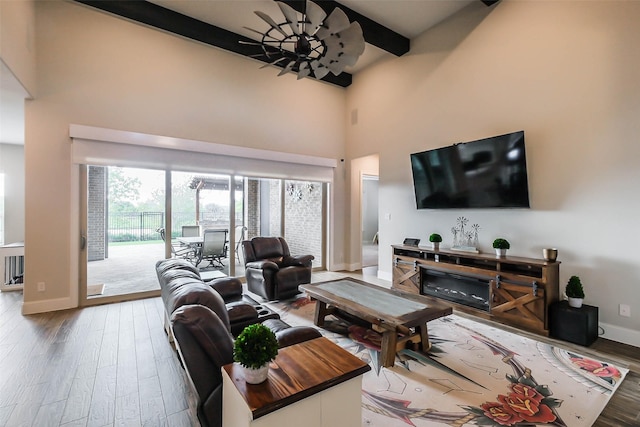 living room featuring a wealth of natural light, beamed ceiling, ceiling fan, and wood-type flooring