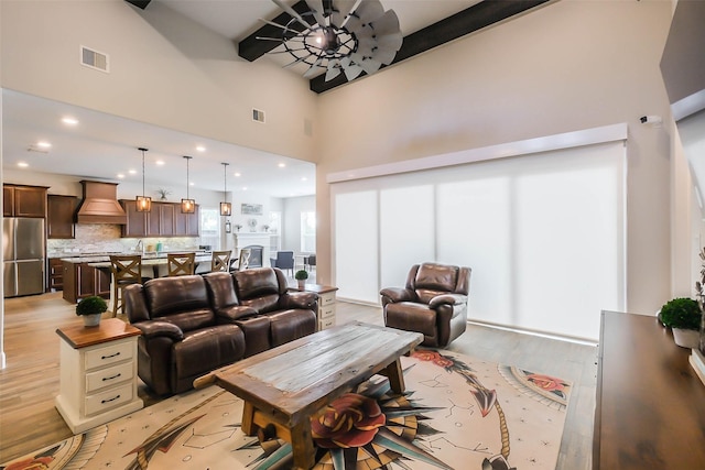 living room with ceiling fan, light hardwood / wood-style floors, and a high ceiling