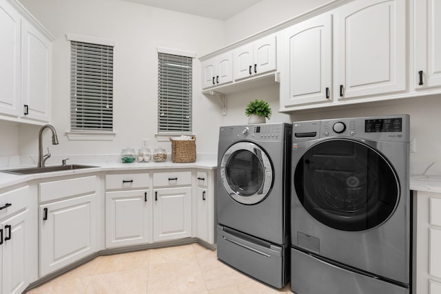 washroom featuring washing machine and clothes dryer, light tile patterned flooring, cabinets, and sink