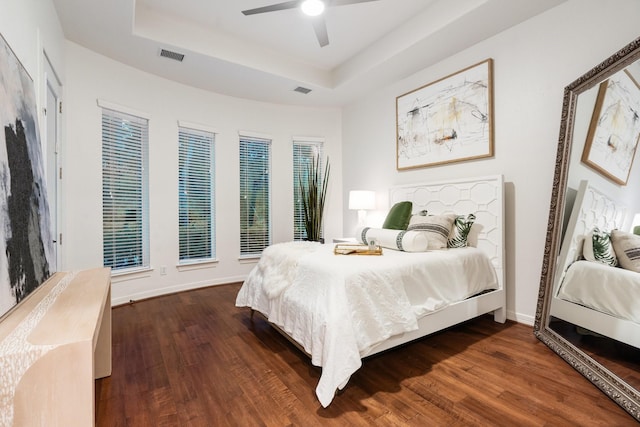 bedroom featuring dark hardwood / wood-style flooring, a raised ceiling, and ceiling fan