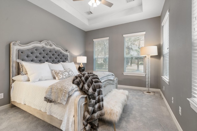 bedroom with carpet flooring, a raised ceiling, and ceiling fan