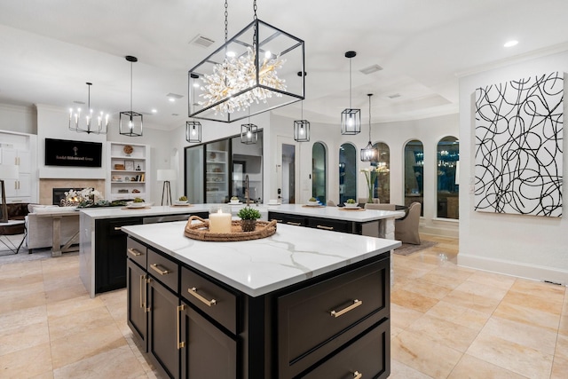 kitchen featuring pendant lighting, a center island, light stone counters, and crown molding