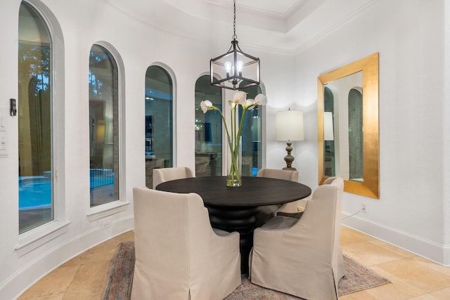 dining space with a raised ceiling, ornamental molding, and a notable chandelier