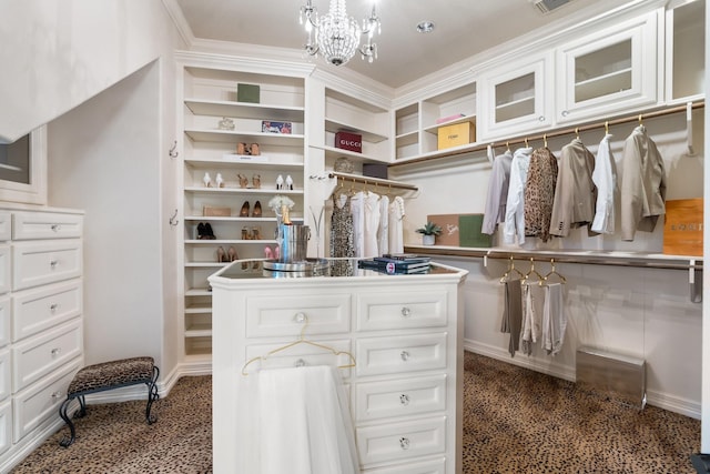 spacious closet featuring dark colored carpet and an inviting chandelier